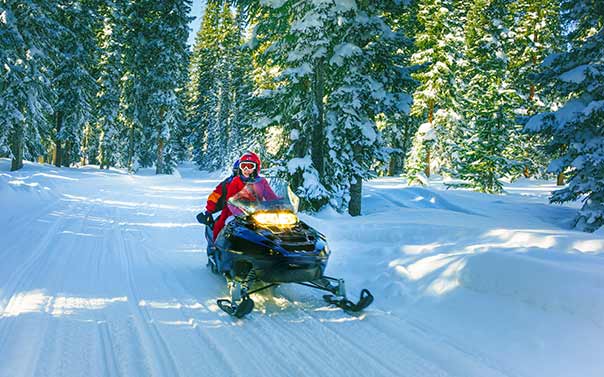 A couple dressed in red riding a black snowmobile